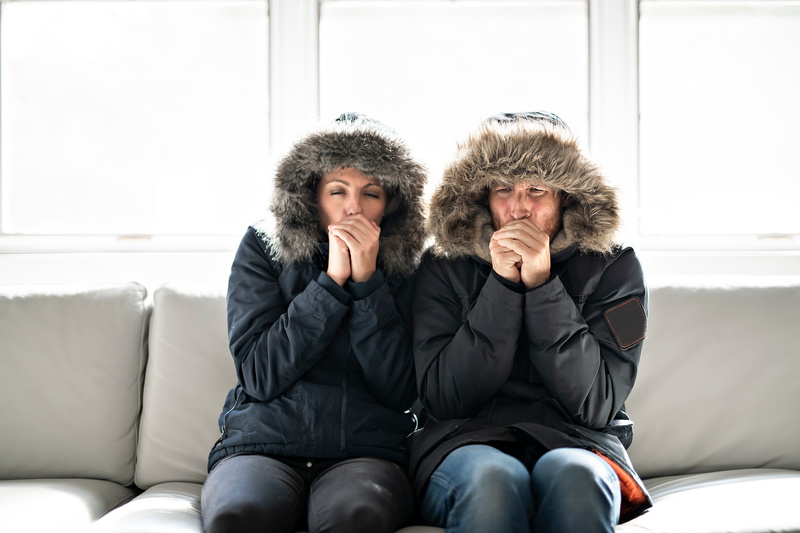 couple-sitting-on-couch-with-parkas-on