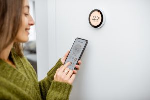 woman-controlling-thermostat-from-smart-phone