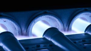 Close-up of a gas furnace burner with blue flames