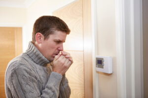 man-looking-at-thermostat-on-a-cold-day