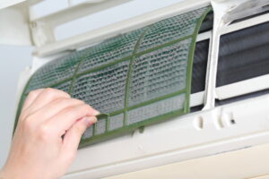 Hand removing an air filter from a heat pump unit for maintenance or repair