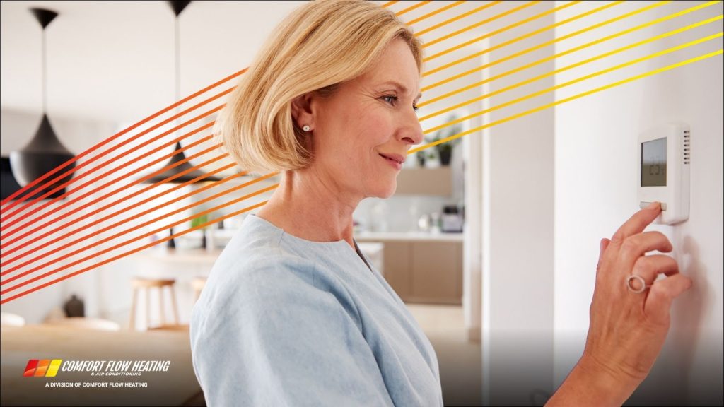 A woman adjusting her smart thermostat